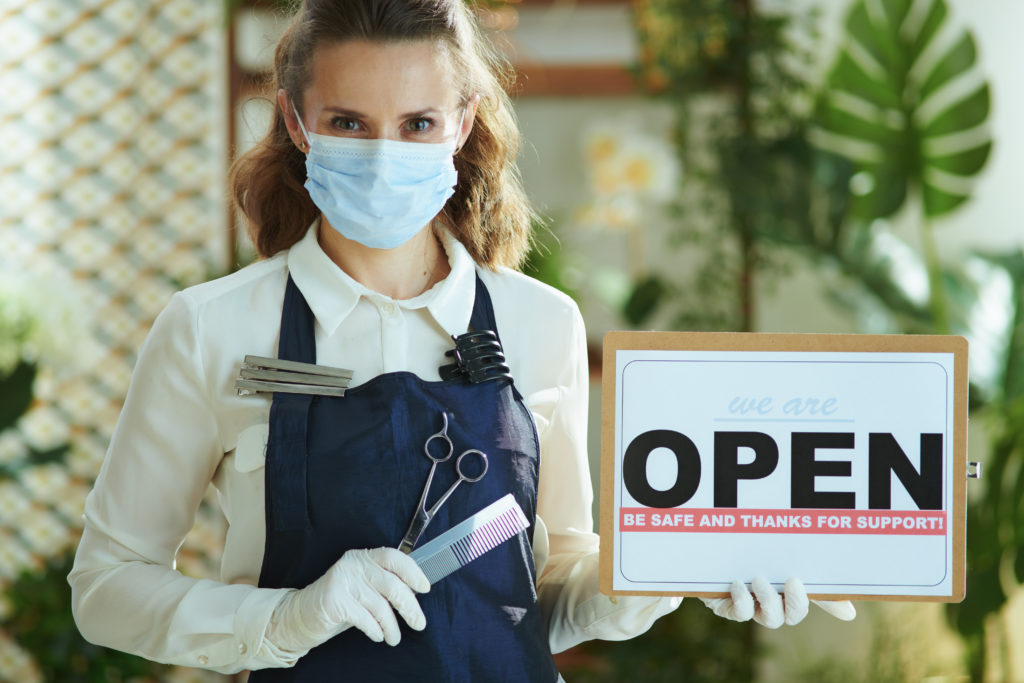 elegant small business owner woman in apron showing open sign