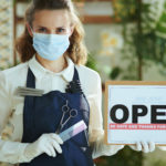 elegant small business owner woman in apron showing open sign